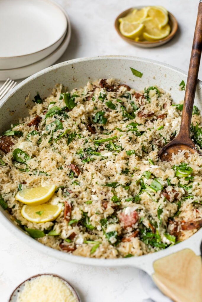 Un frasco de pollo al limón, salchicha, espinacas y arroz